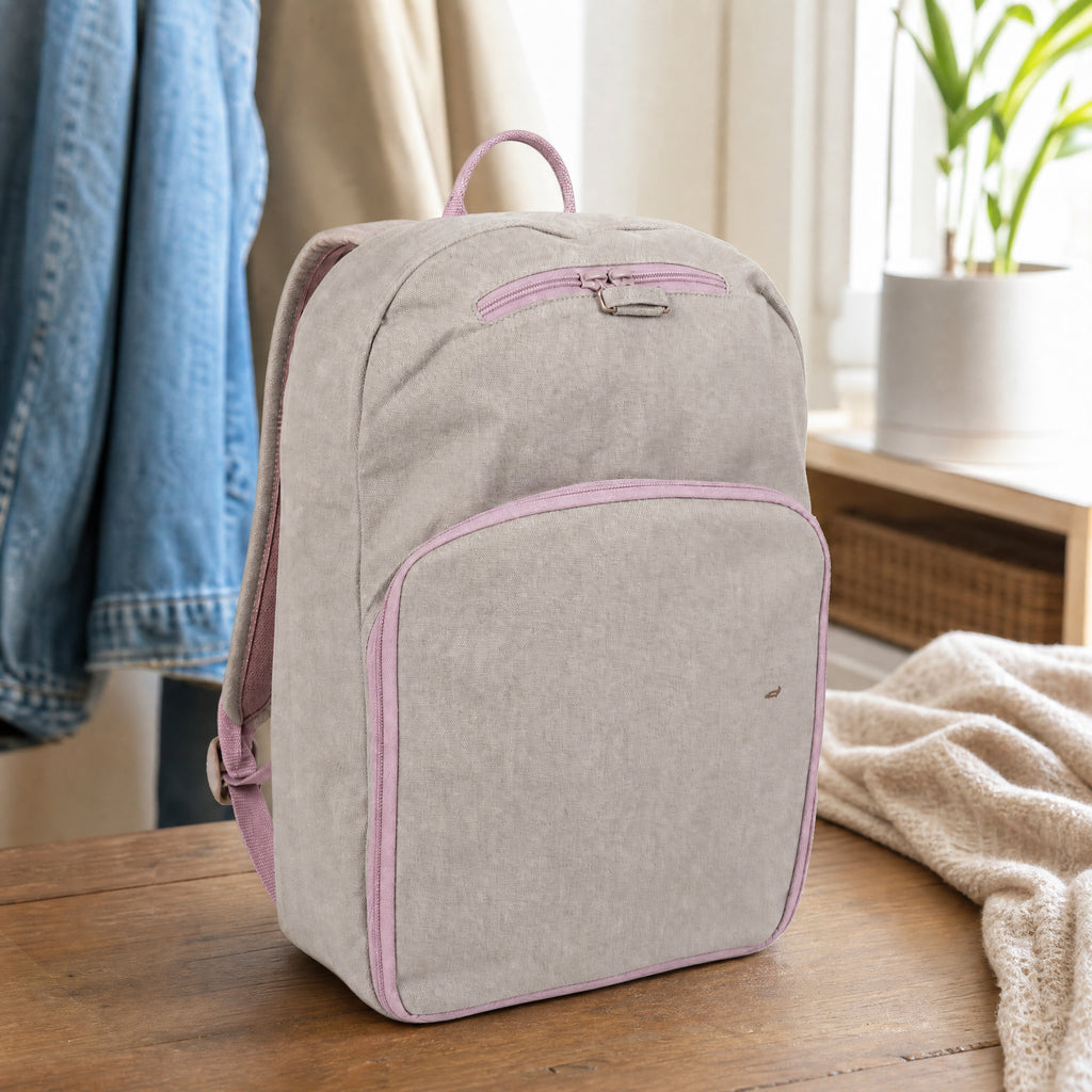 Mochila gris con ribetes y cremalleras rosas, bolsillo frontal y pequeña mancha