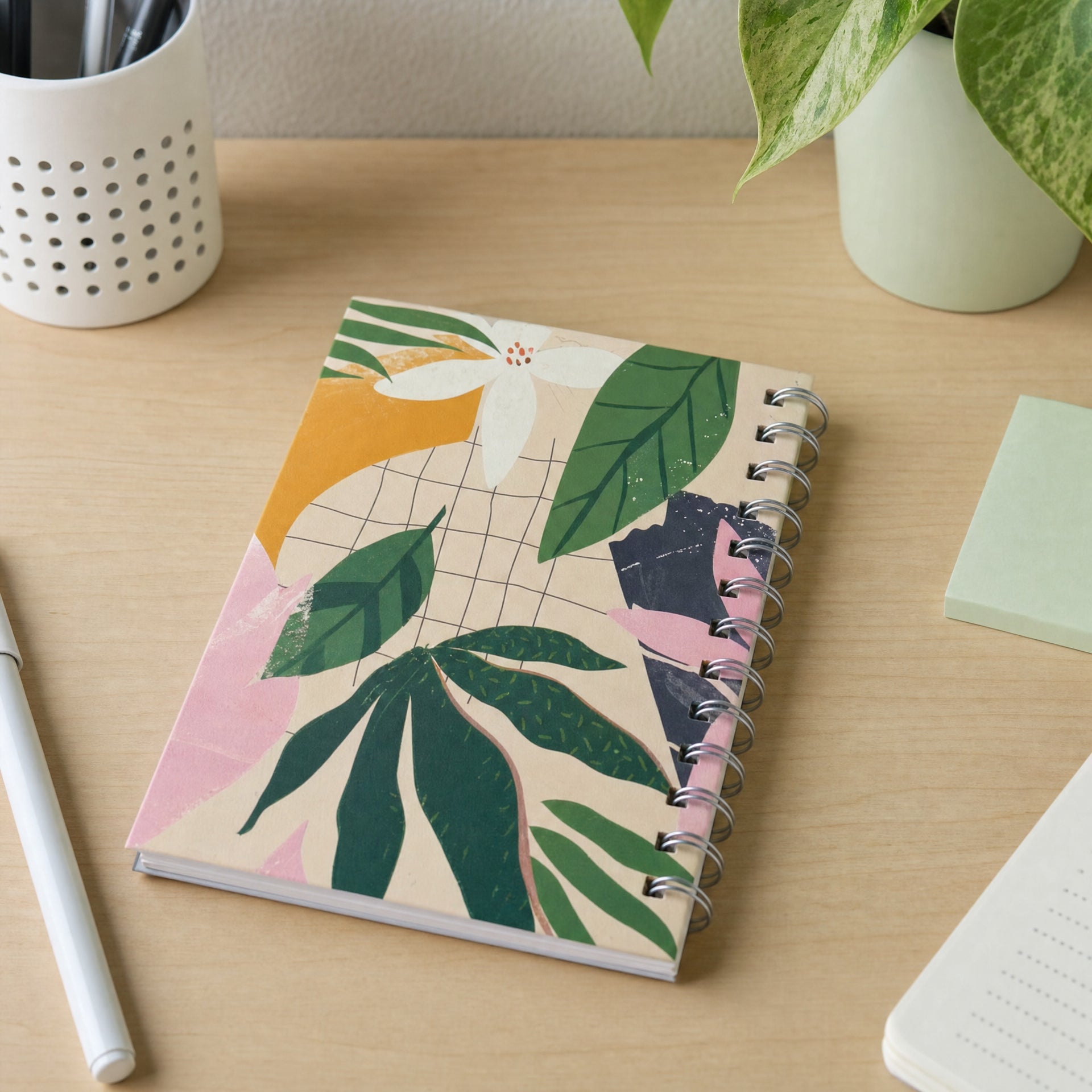 Cuaderno en espiral con portada impresa de hojas tropicales y flores sobre patrón cuadriculado