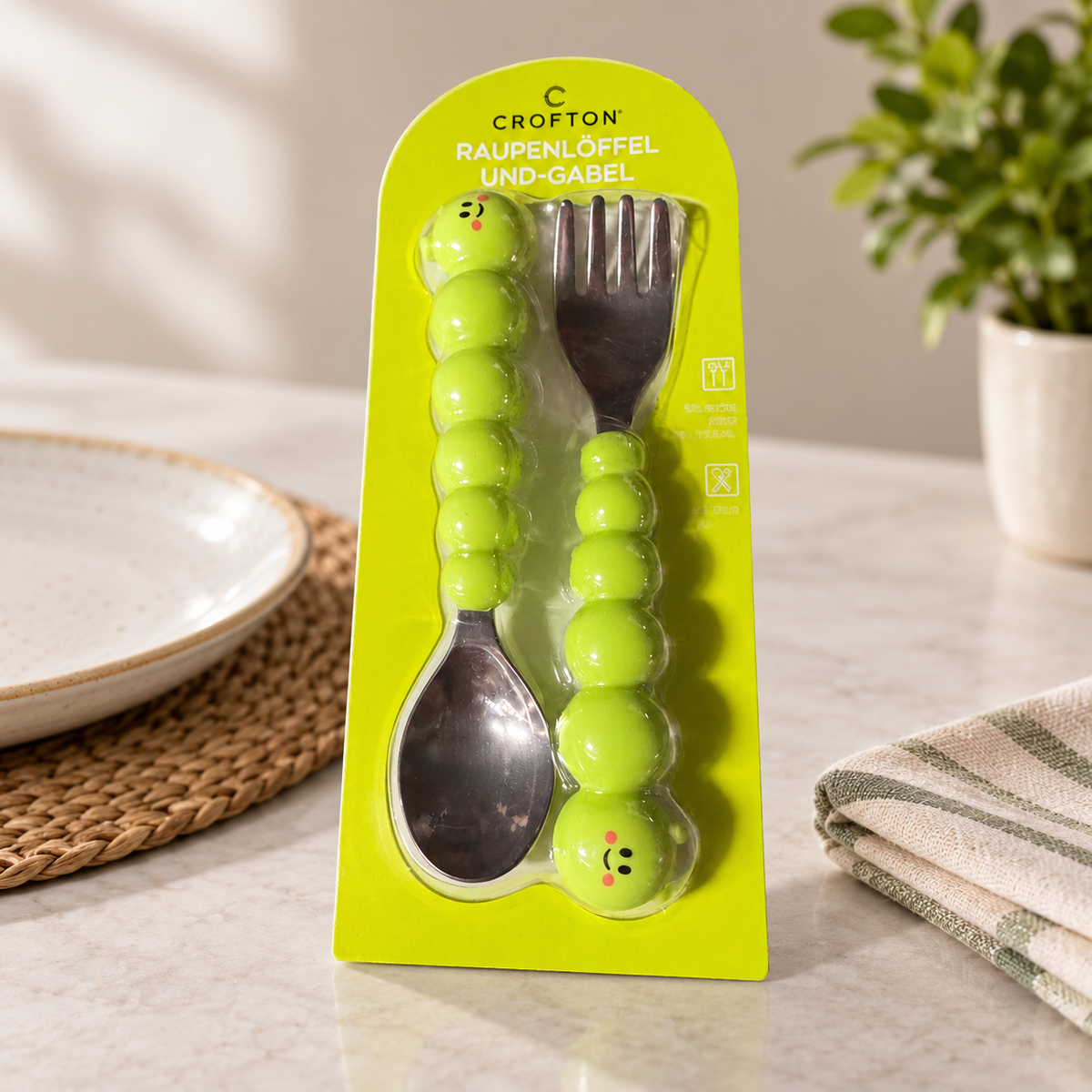 Cubiertos Crofton con mangos de oruga en su envase sobre una mesa de comedor