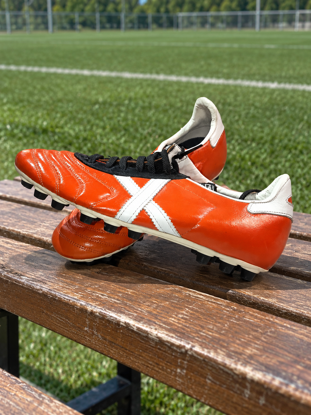 Par botas Munich naranjas talla40 sobre banco junto a campo, con marcas visibles