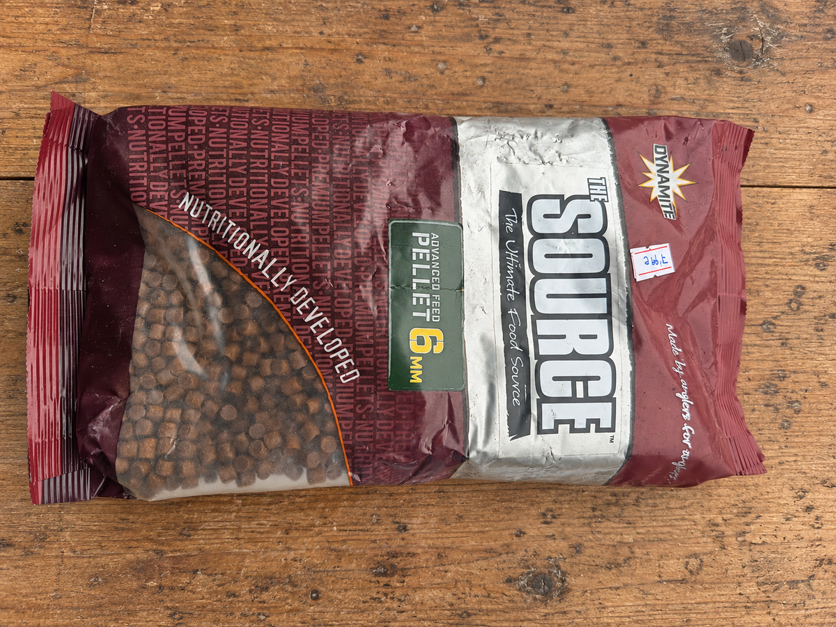 Bolsa Dynamite The Source pellets 6 mm sobre mesa de madera