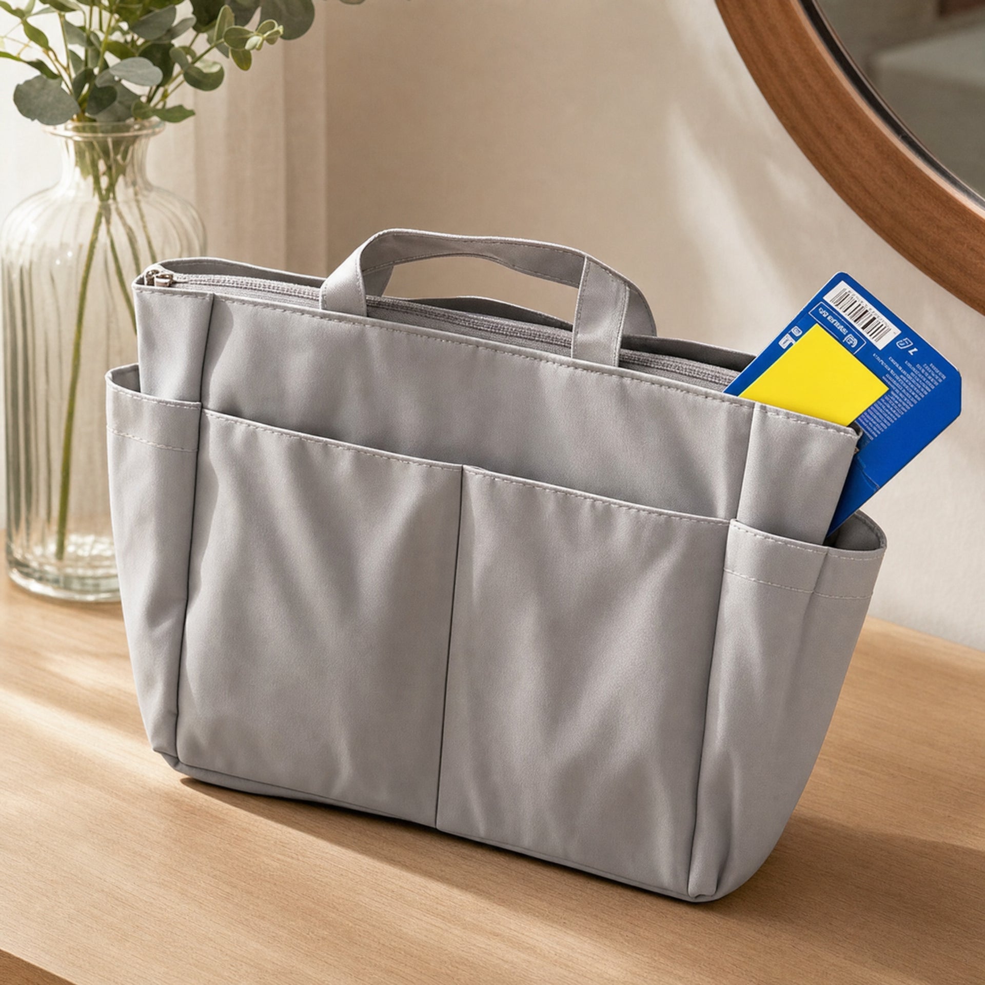 Organizador de bolso gris con asas superiores, bolsillos exteriores y cremallera superior