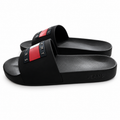 Par de chanclas Tommy Jeans negras con logo de bandera sobre fondo blanco